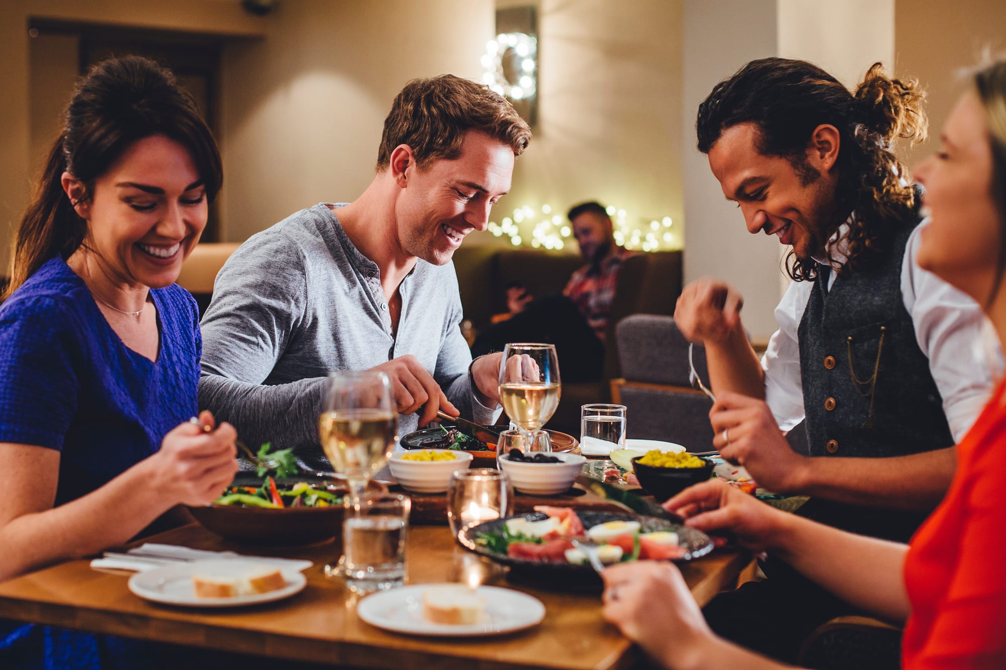 Four guests in a restaurant enjoying prix fixe meals and wine drinks.