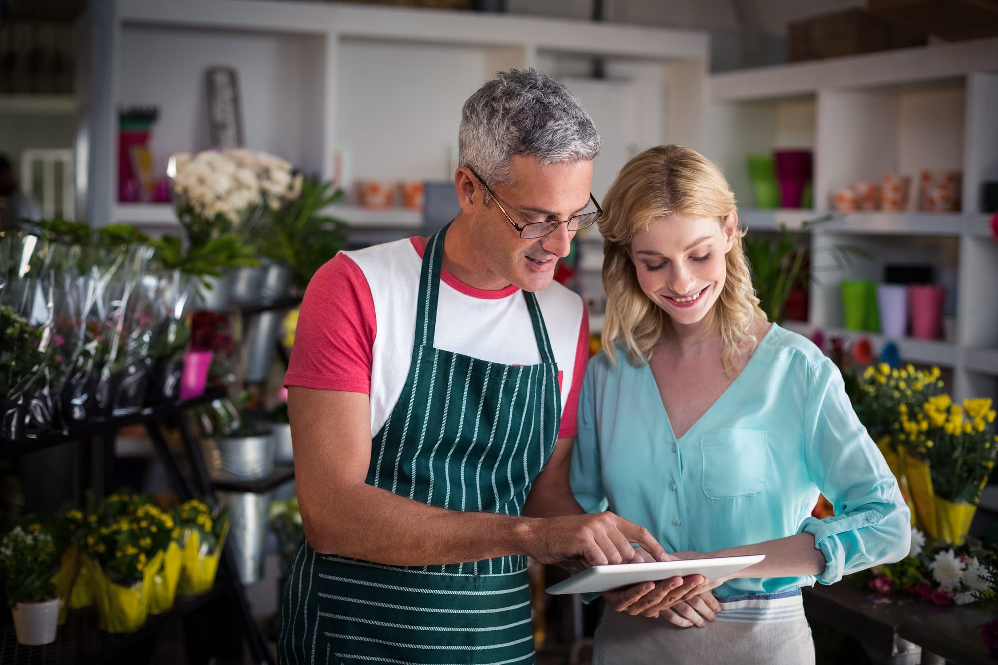 Two business owners in a flower shop research for keywords on Google