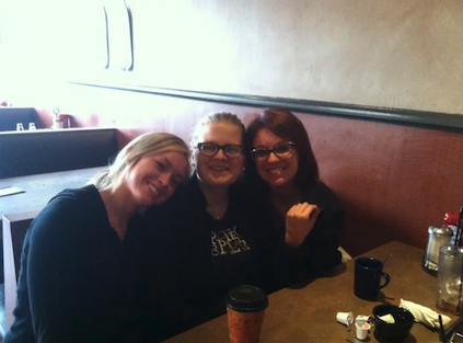 Three women at restaurant smiling with food cafe order point of sale system.