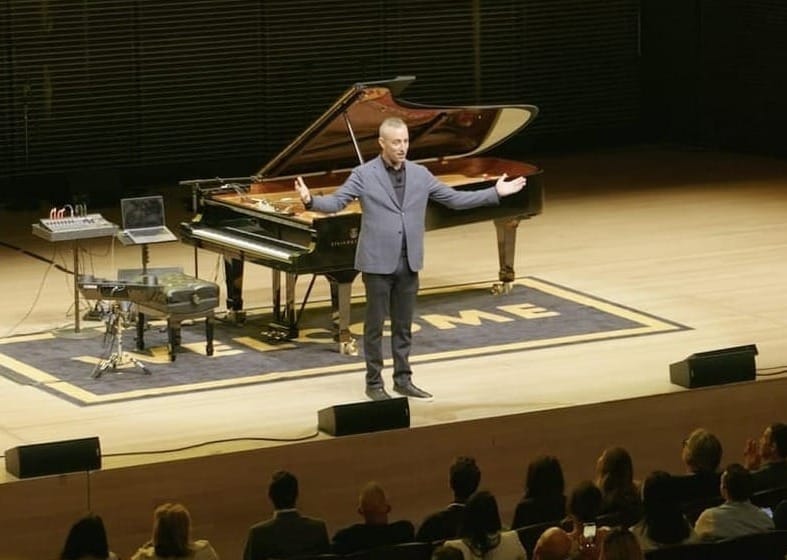 Will Guidara standing on stage in front of a piano.