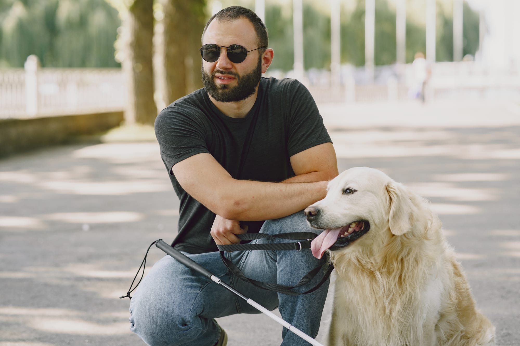 A blind man poses next to his service dog on a summer day.