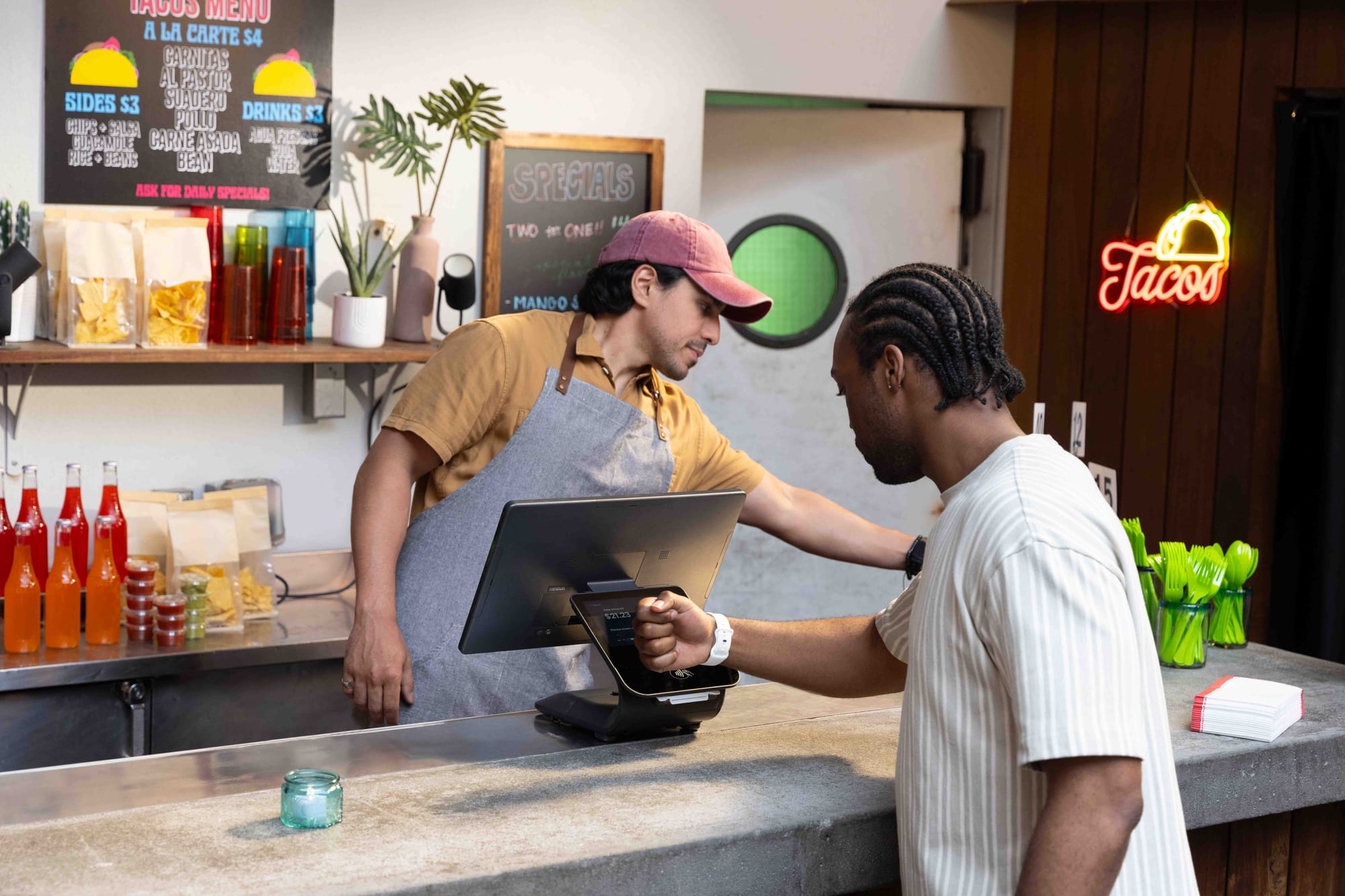 A customer taps his smart watch to the POS to pay for his food at a restaurant