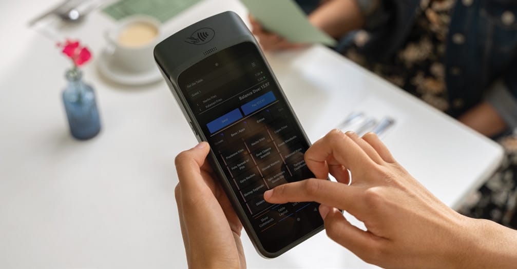 A handheld in a person's hands with a table in the background.