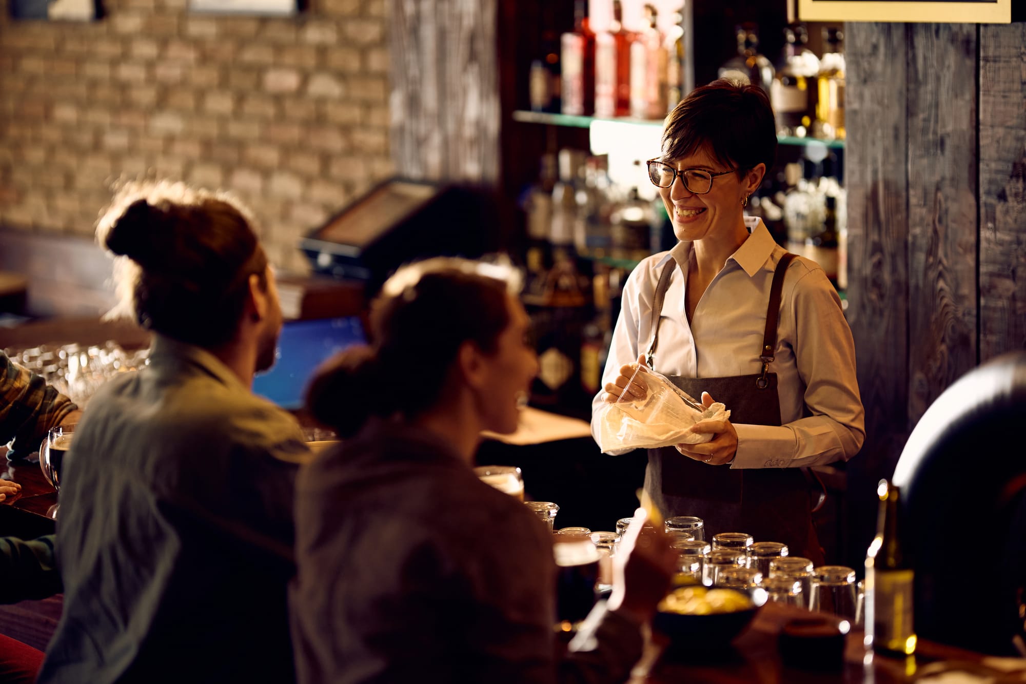 bartender at a bar smiling and talking to bar patron