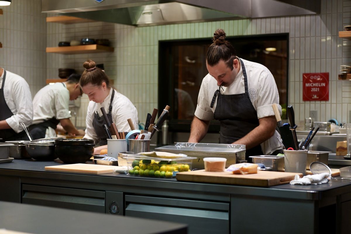 Two chefs preparing food in the kitchen, with a Michelin Star 2021 plaque in the background