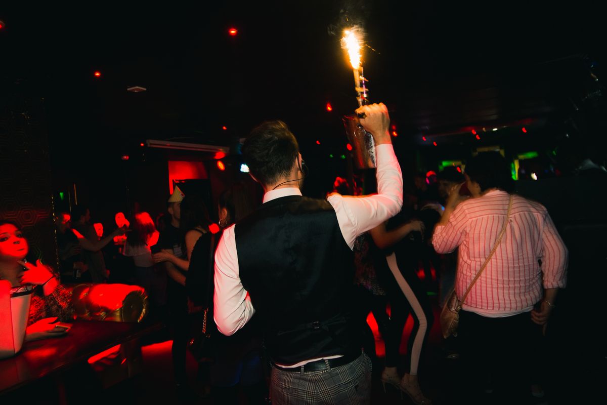 A server delivers a bottle of champagne to a VIP table as part of a club's VIP bottle service