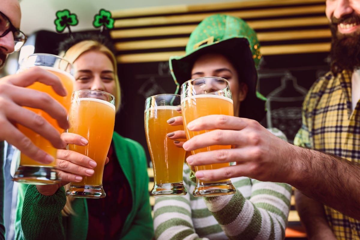 Four people toasting with beer at a St. Patrick's Day bar crawl.