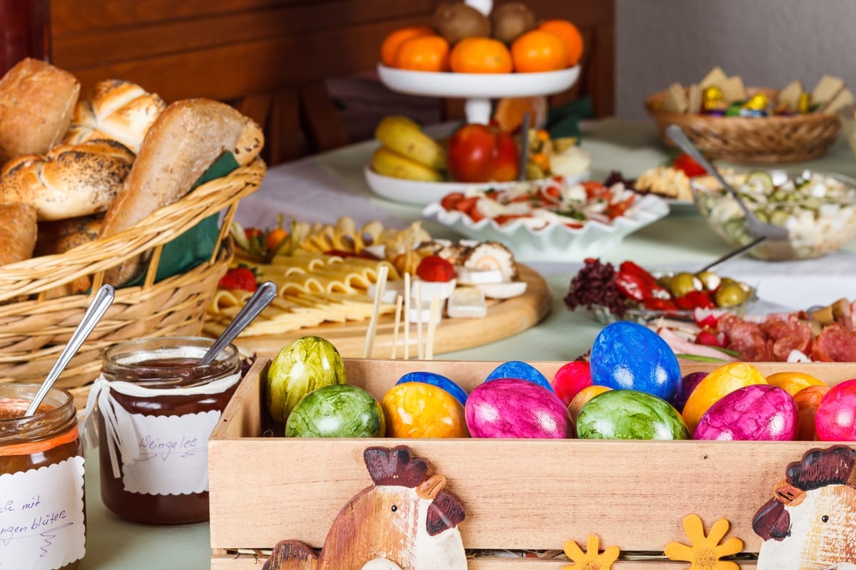 Easter eggs, bread, jam, and fruit on a table.