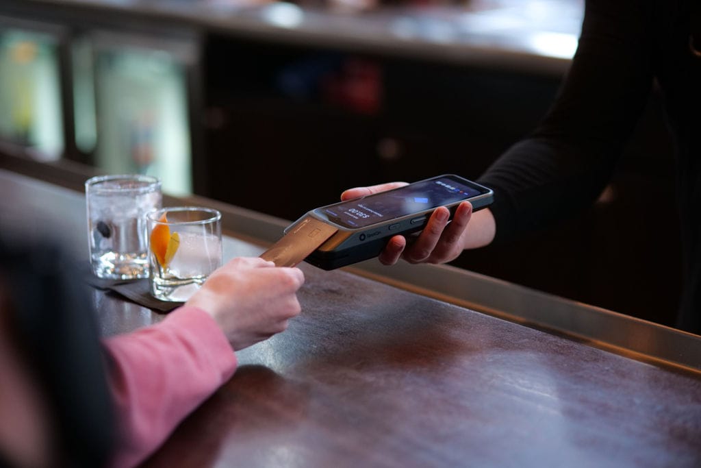 Restaurant guest pays by handheld pos system.