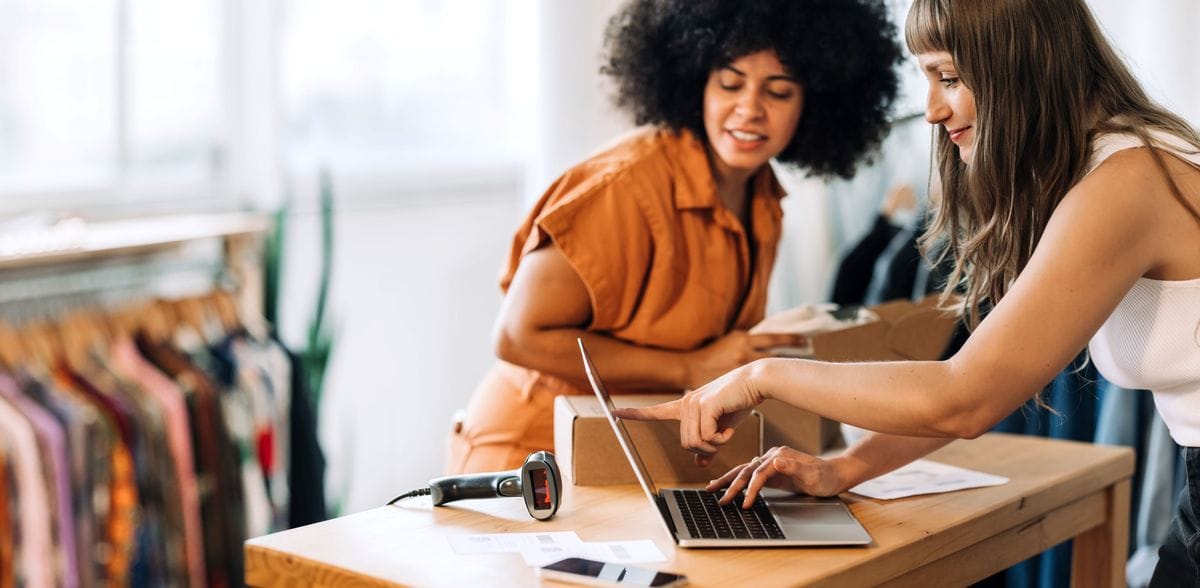 Two small business owners review their customer mailing list on a laptop computer